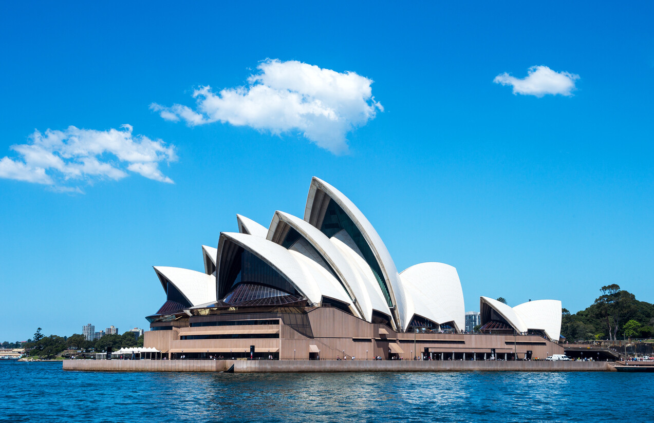 Sydney Opera House with its iconic white sail-shaped shells overlooking Sydney Harbour on a bright, clear day