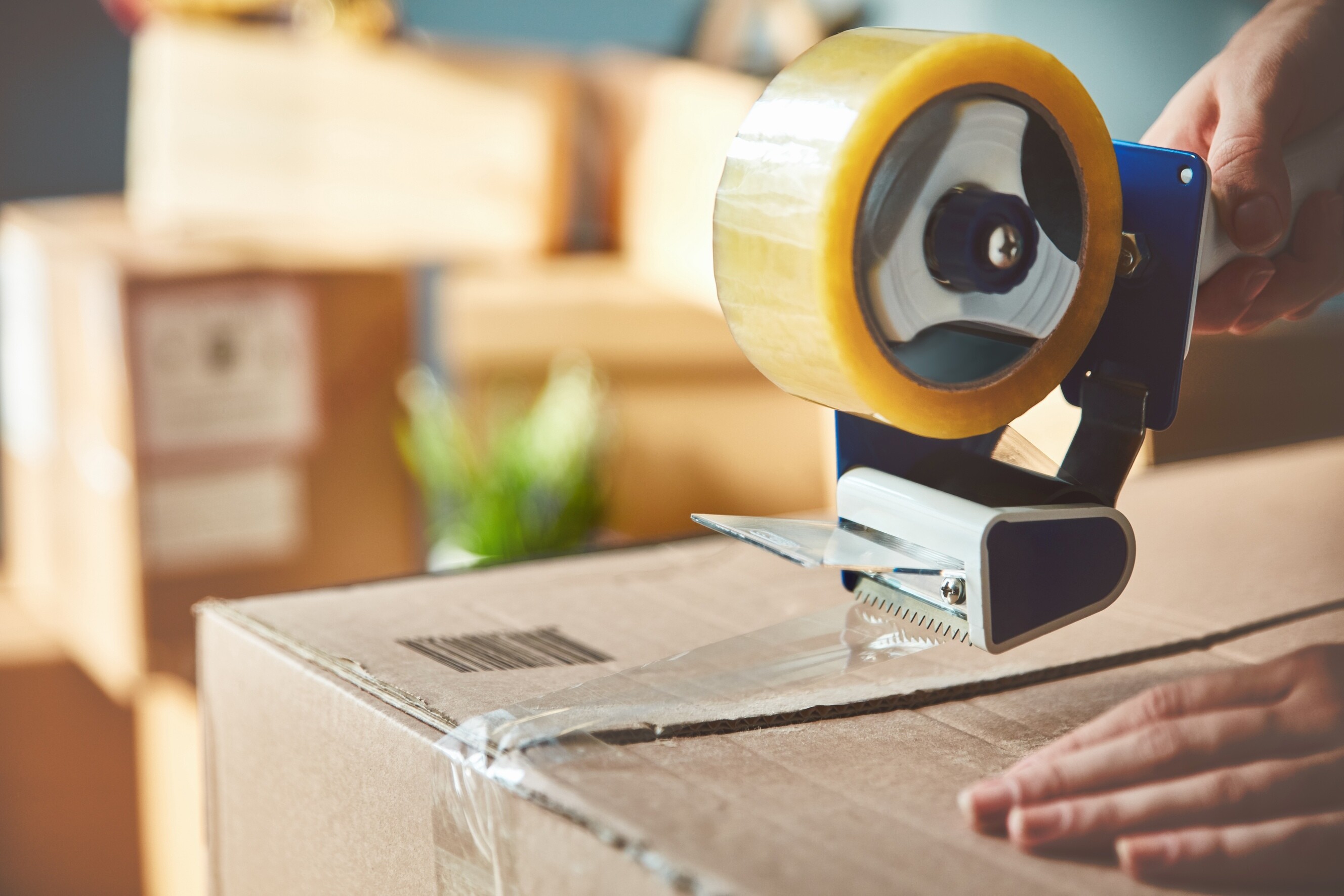 A person carefully taping a cardboard box securely to prepare for moving.