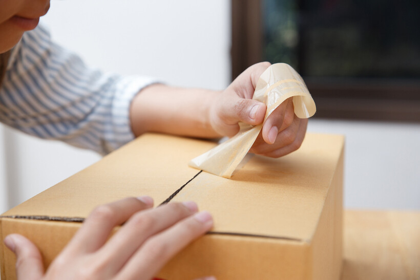 A person happily opening a taped cardboard box to unpack their items. - duct tape vs packing tape