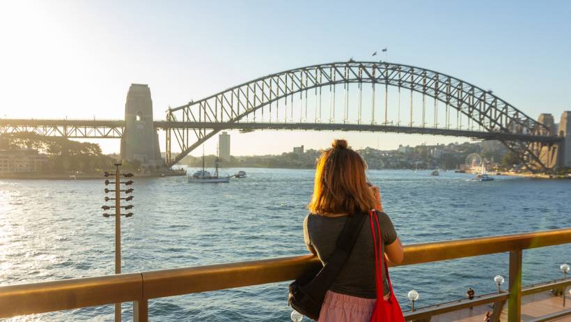 Woman photographing Sydney Harbour Bridge at sunset. - moving to sydney
