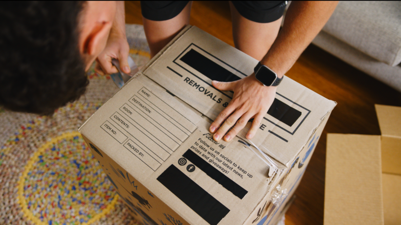 a man packing moving boxes - moving to sydney