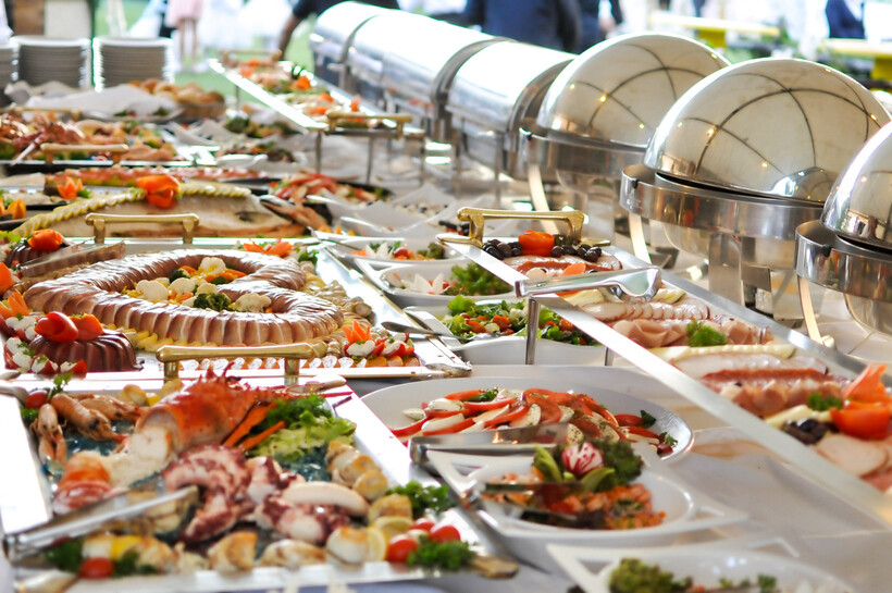 A variety of delicious food dishes arranged on a long table for self-service dining. - plated vs buffet