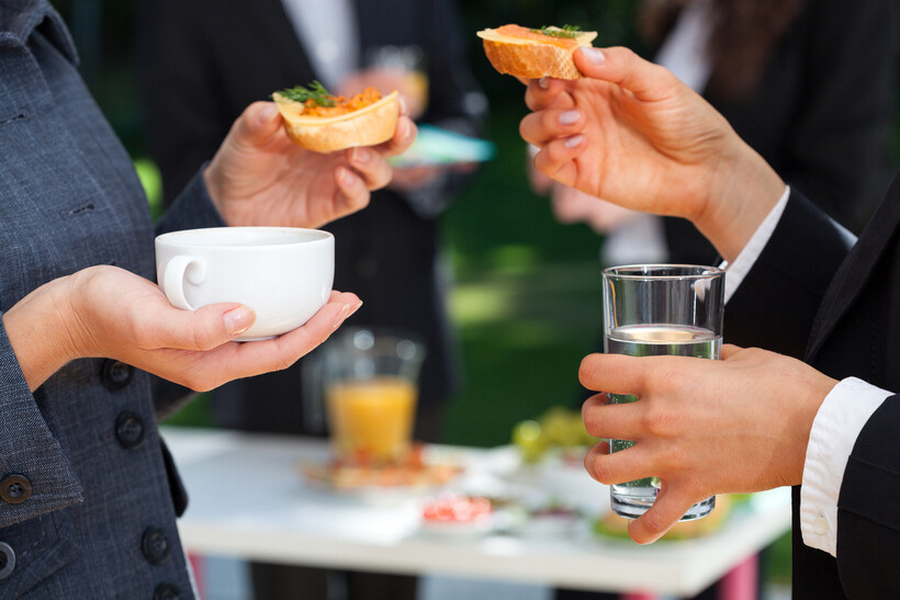 Coworkers near a table sharing a selection of different catering dishes. - plated vs buffet
