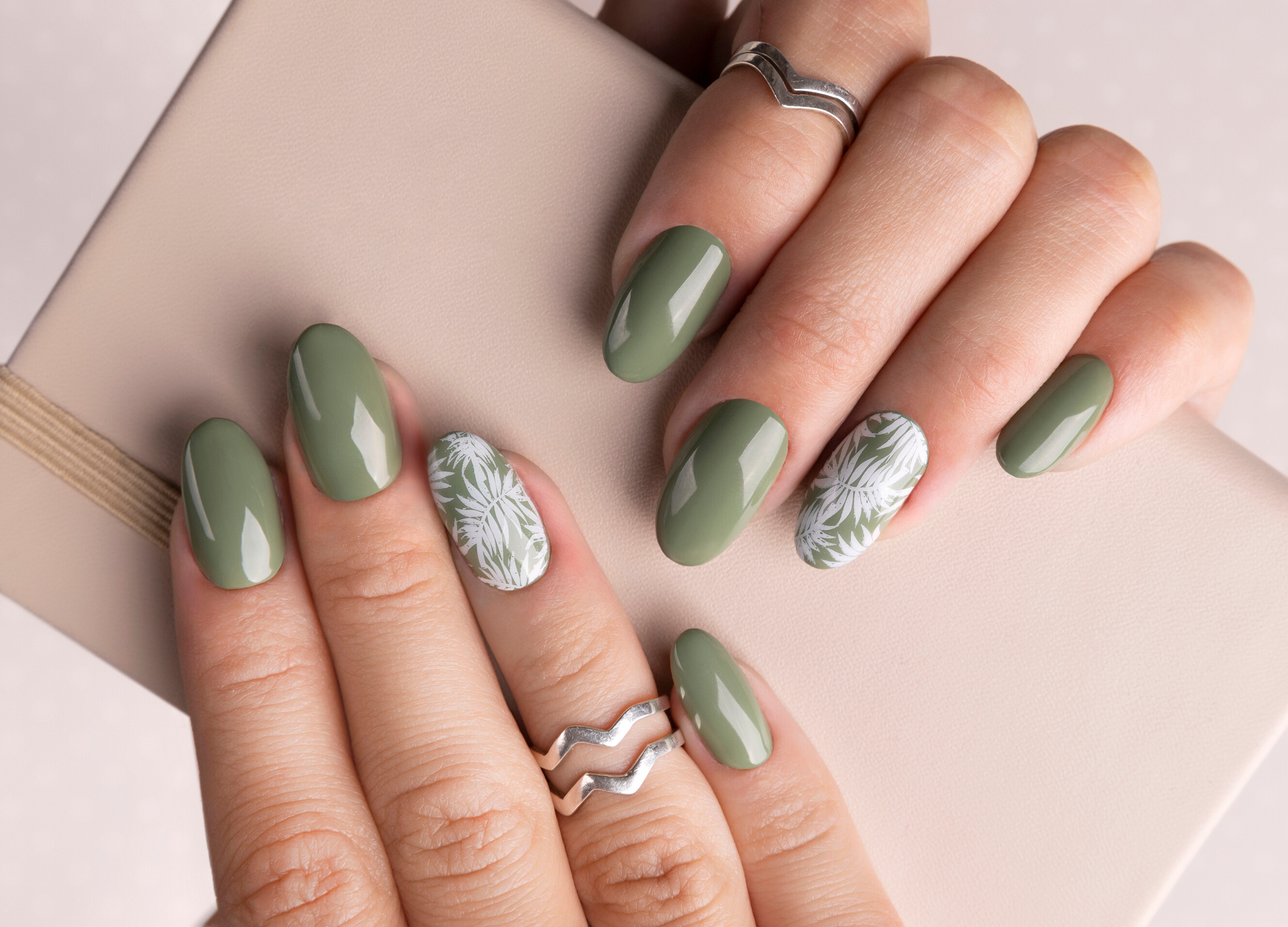 A woman’s hands featuring delicate floral nail art designs in vibrant spring and summer colors.