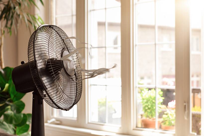 fan vs air conditioner - Floor-standing electric fan used for cooling in a bright indoor space