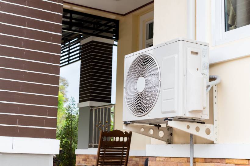 fan vs air conditioner - Outdoor unit of a wall-mounted split air conditioner installed on a residential building