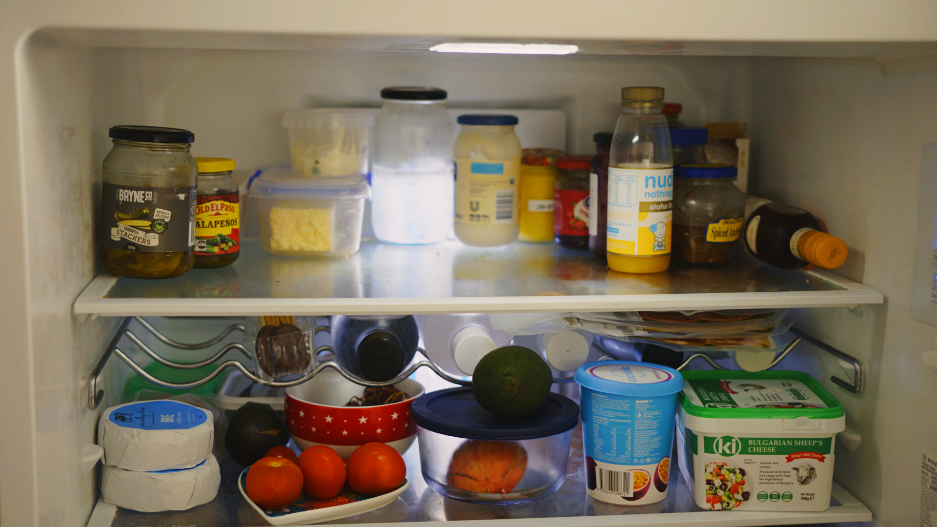 cost to move fridge - Interior of a refrigerator filled with food containers, jars, and fresh produce