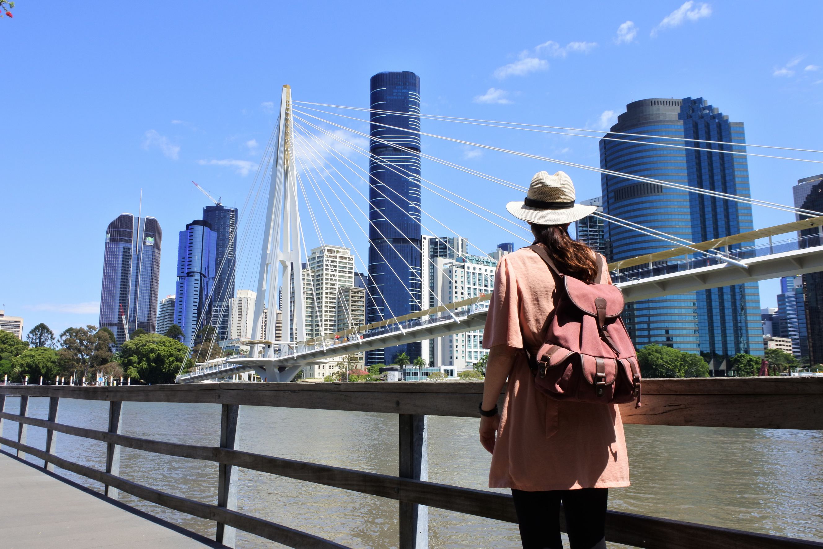 Rear view of adult Australian woman looking at Kangaroo Point Bridge, representing Adelaide to Brisbane moving services.
