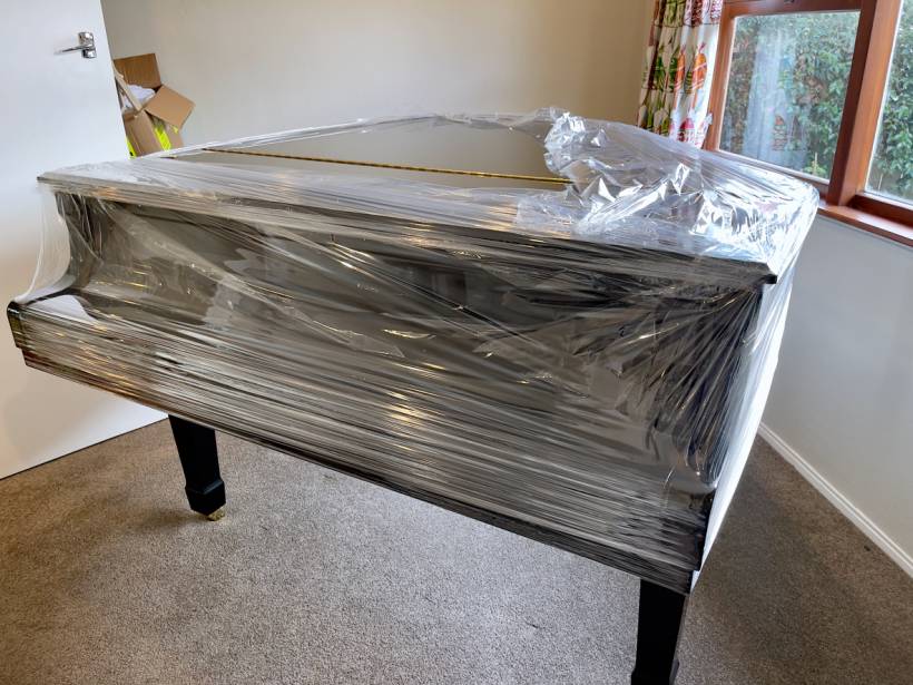 cost to move a piano - Grand piano wrapped in protective plastic, prepared for moving