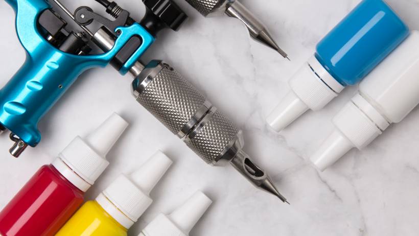 Tattoo tools and equipment laid out on a white marble table. - making money as a tattoo artist