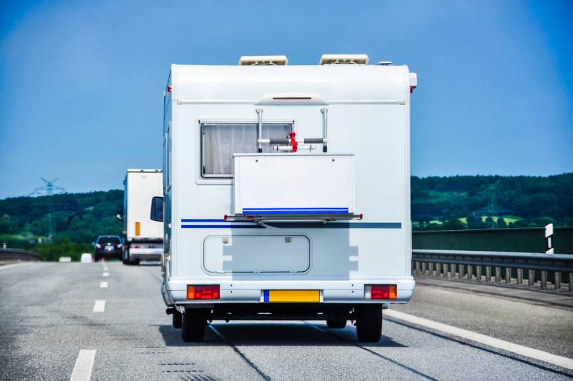 cost to move a shed - Motorhome or portable structure moving along a highway under blue sky