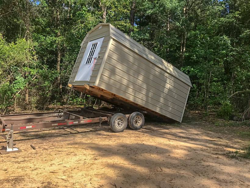 cost to move a shed - Shed being unloaded from a tilt trailer in a rural area