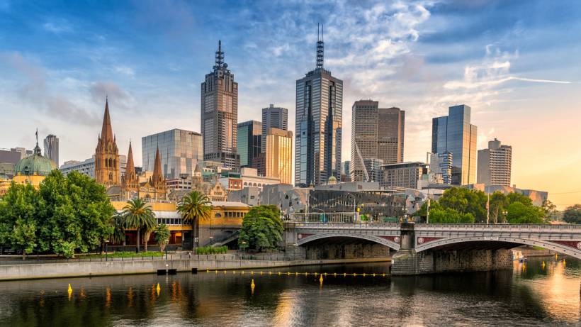 A wide-angle view of the Yarra River Melbourne waterfront featuring urban skyscrapers reflected in the water during golden hour. - relocating to melbourne