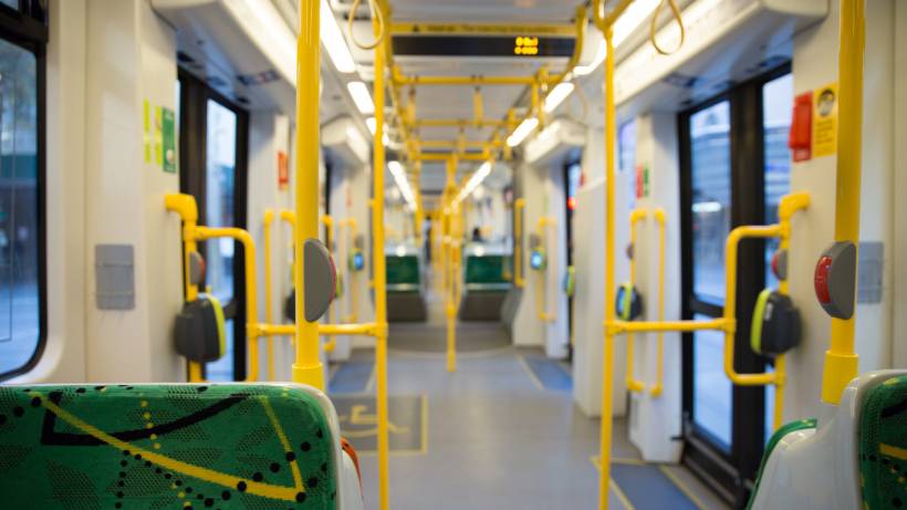 Interior view of a modern Melbourne public transport tram showing yellow handrails, green patterned seating, and digital display screens. - melbourne living transportation