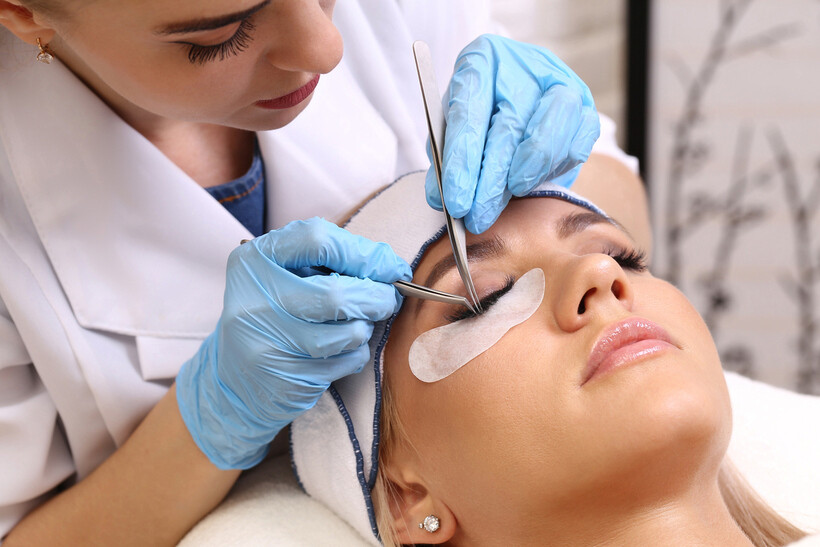 A specialist using tools to apply individual synthetic lashes during a treatment session. - lash lift and tint vs extensions