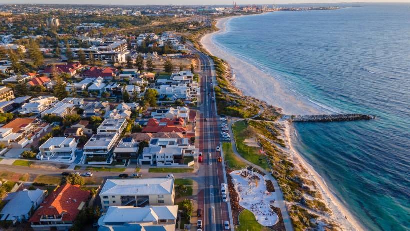 Aerial view of the cityscape of Cottesloe featuring coastal residential buildings, Marine Parade, and the white sands of the beach. - relocating to perth