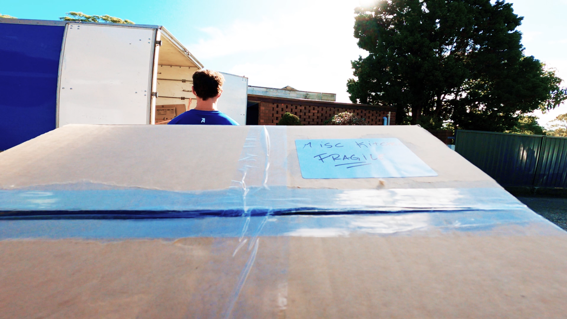 how to pack a moving truck - Loading fragile items into a truck, with a focus on a taped and labeled moving box