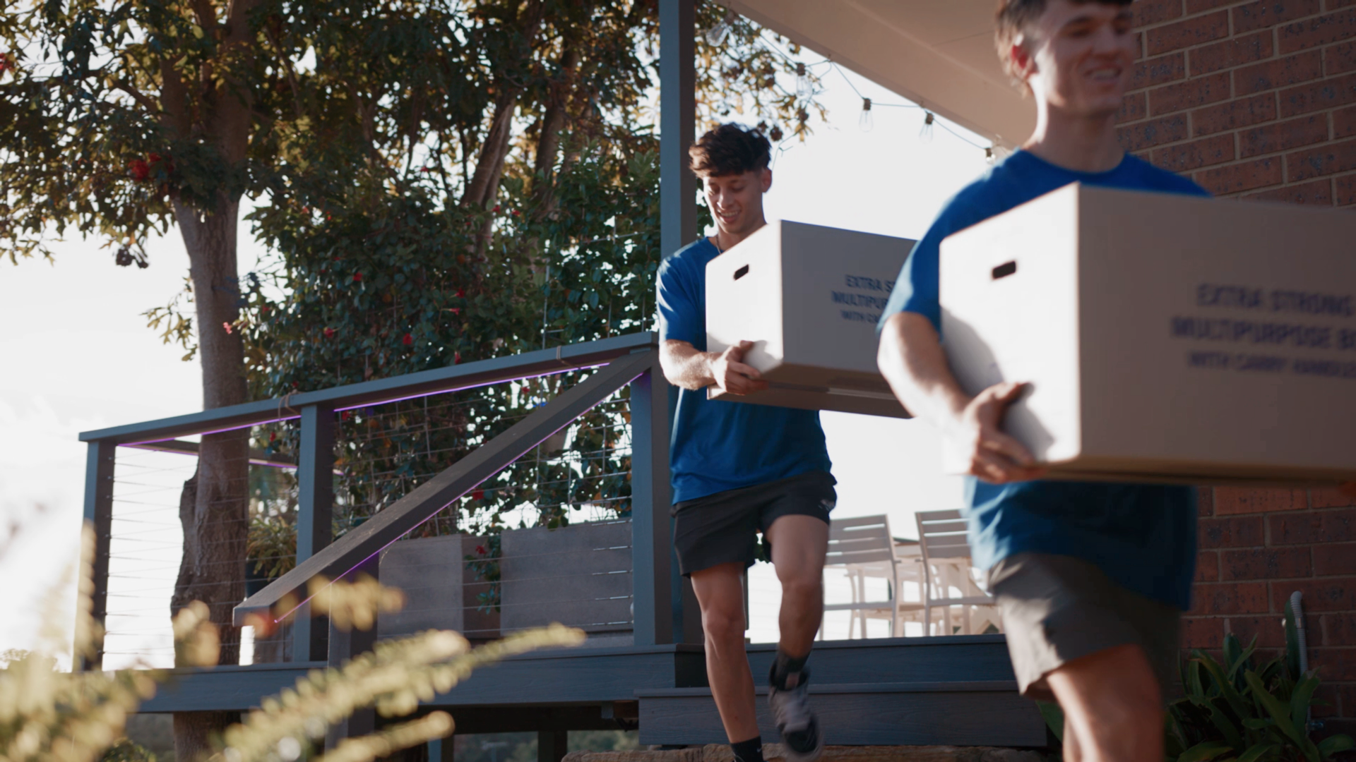 how to pack a moving truck - Taskers working together carrying cardboard boxes down a porch