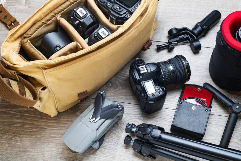 how to make money with photography - Flat lay of professional photography gear including cameras, lenses, drone, and tripod beside a padded camera bag