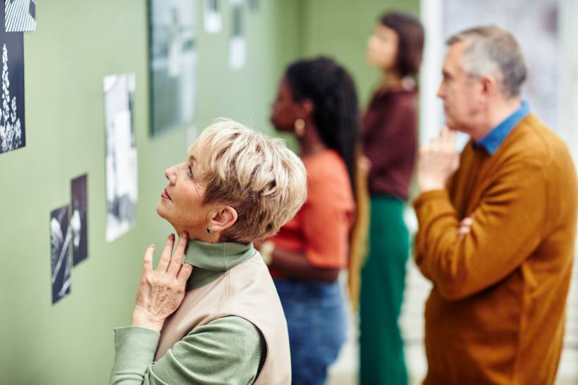 how to make money with photography - Visitors observing black and white prints at a photographer exhibit in a gallery