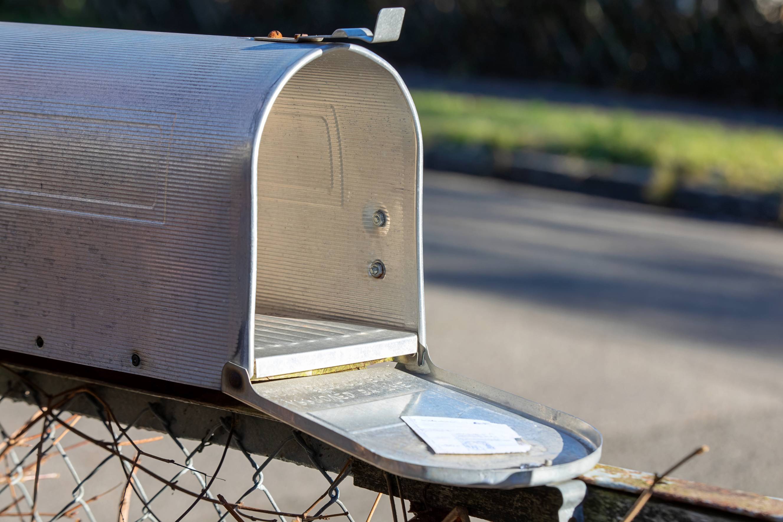 an open letterbox installed on top of a fence