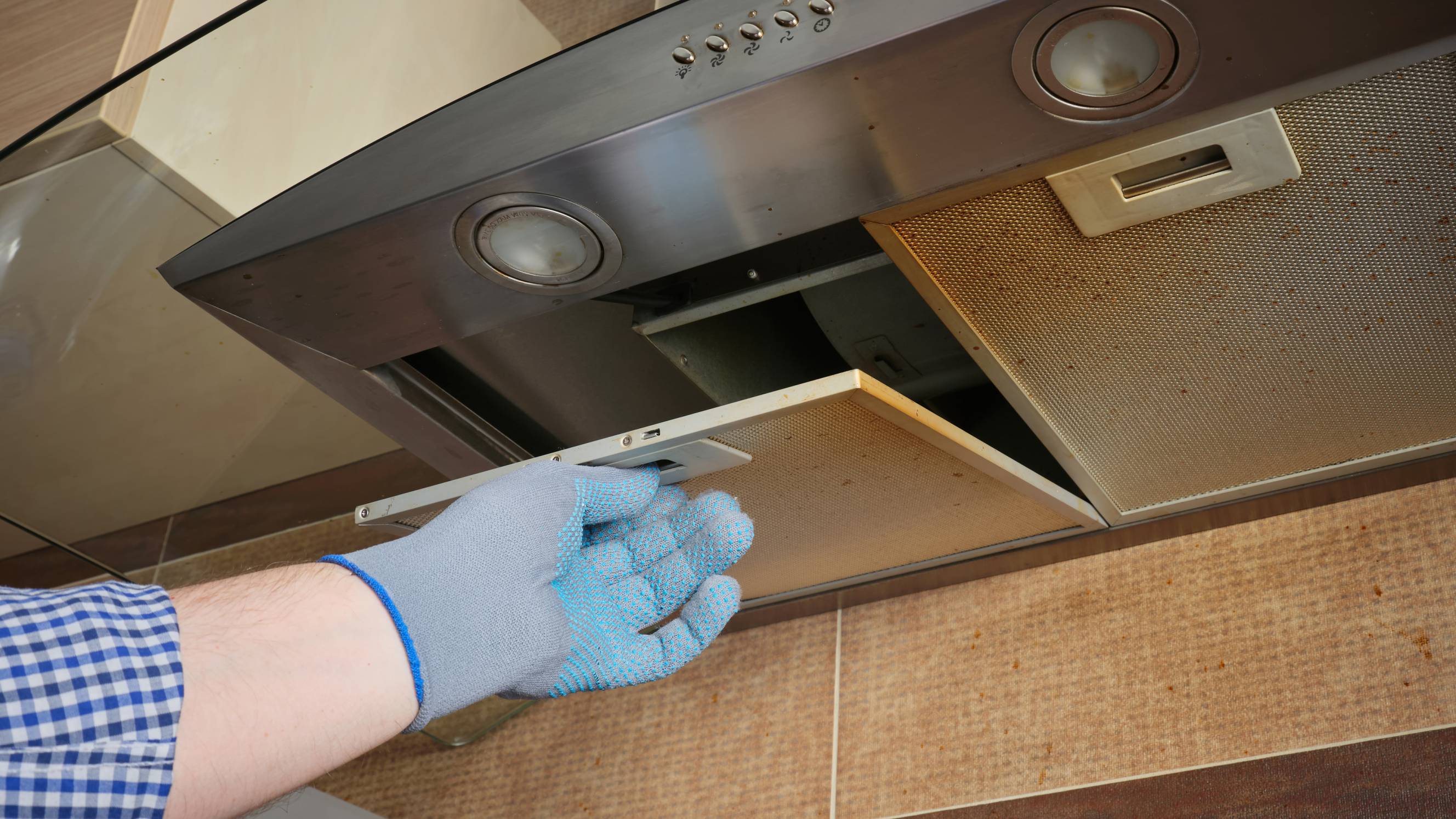 a professional cleaner reaching for the rangehood to remove the filter for cleaning
