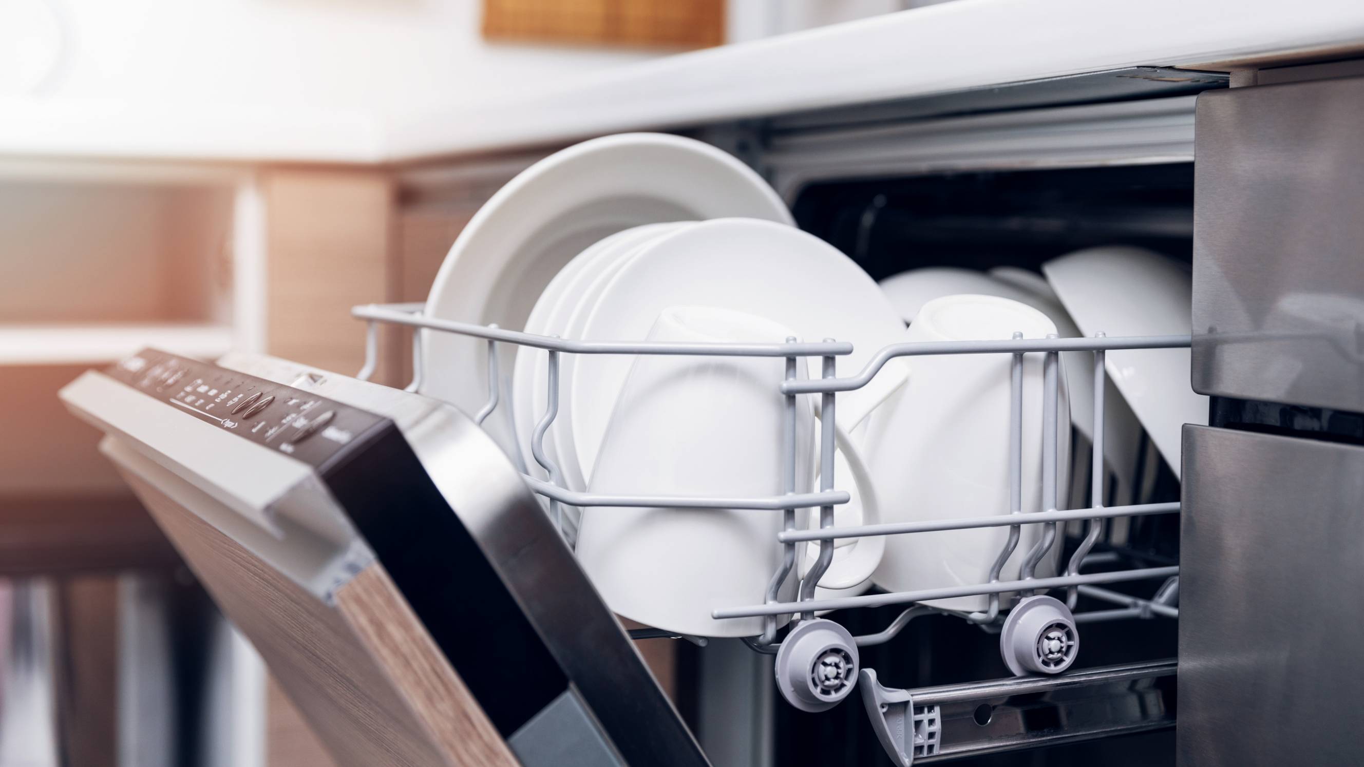 a close up photo of an open dishwasher full of white plates