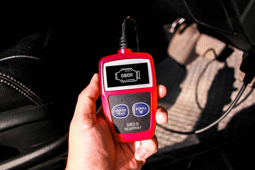 car diagnostic test cost - OBD2 scanner connected below car dashboard