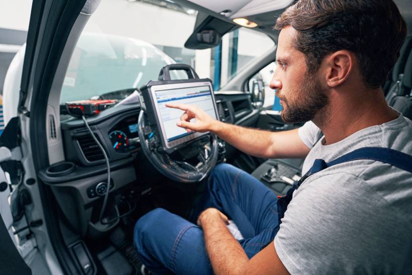 car diagnostic test cost - Technician using diagnostic tablet inside vehicle