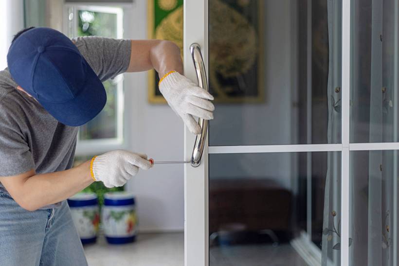 how much does a handyman cost - Handyman tightening a glass door handle with a screwdriver