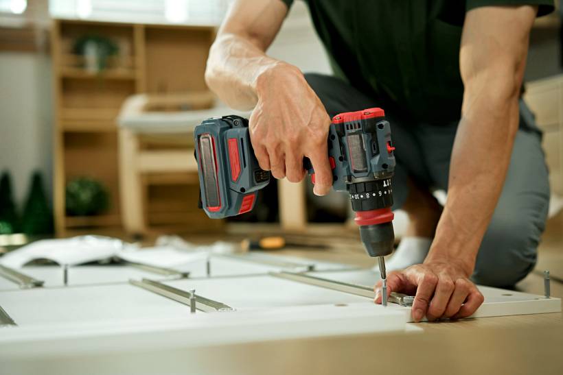how much does a handyman cost - Handyman using a cordless drill to assemble furniture