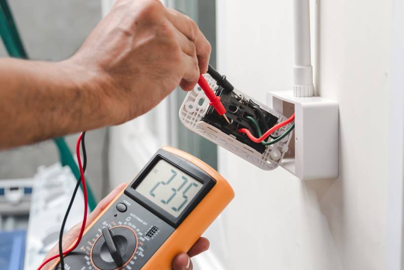 how much does a handyman cost - Handyman checking exposed electrical wiring indoors