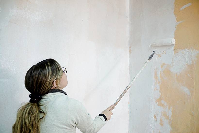 how to limewash walls - Person applying white paint to interior wall with roller