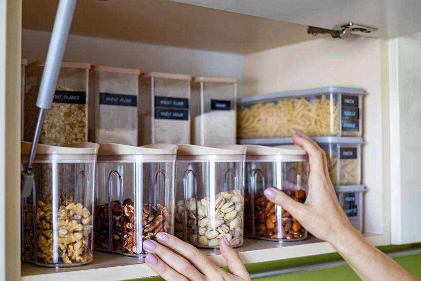professional organiser cost - Pantry shelf with labeled containers of nuts, pasta, grains, and dry goods