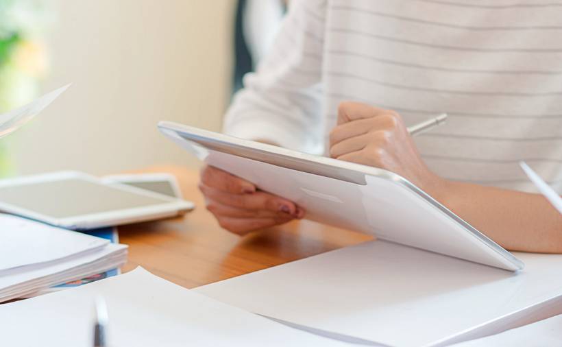 how much does a tax accountant cost - Person using tablet with paperwork on desk