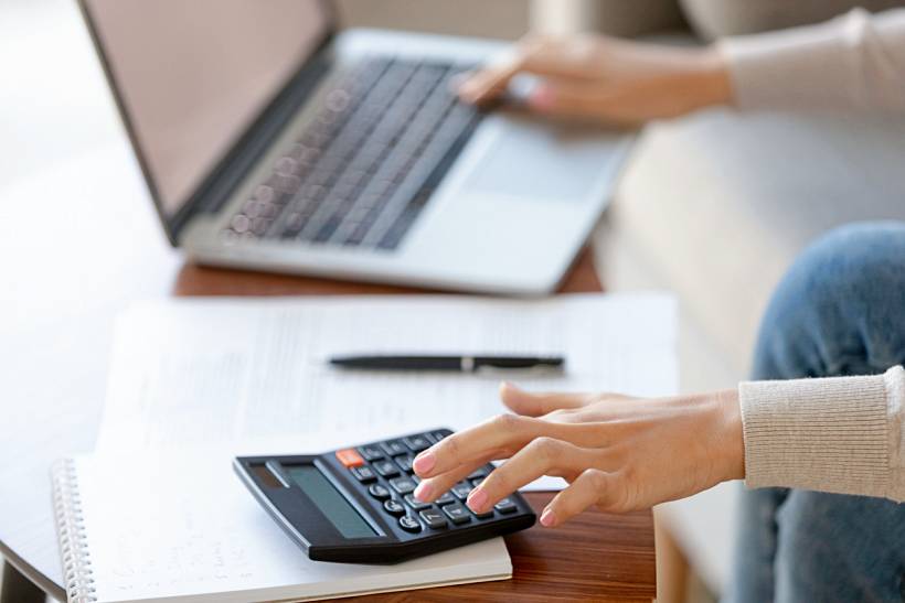 how much does a tax accountant cost - Person using calculator with laptop and documents