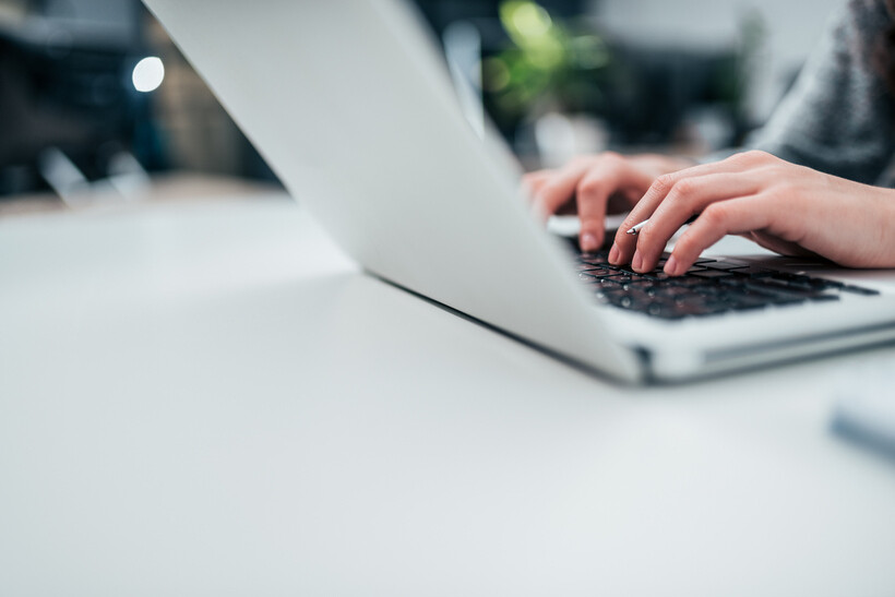 Close-up of a woman’s hands typing on a laptop. - event planning tasks