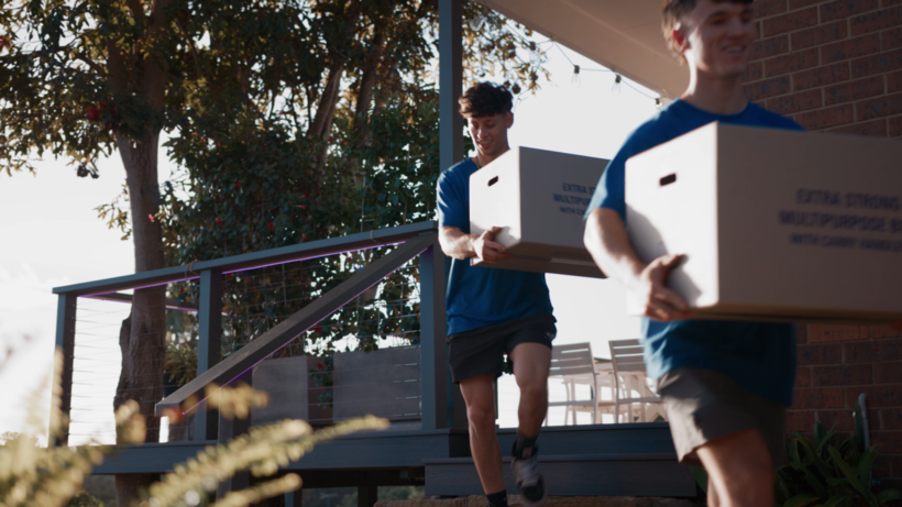 Two men carrying large cardboard boxes down outdoor steps. - event planning tasks