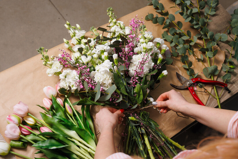 A female florist arranging a spring bouquet inside a flower shop. - event planning tasks