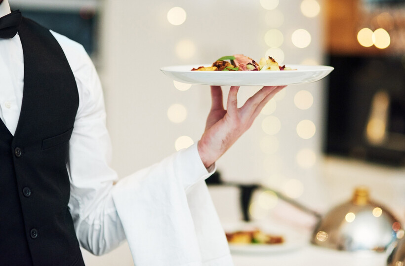 Professional event staff member in a suit serving guests at a function. - event planning tasks