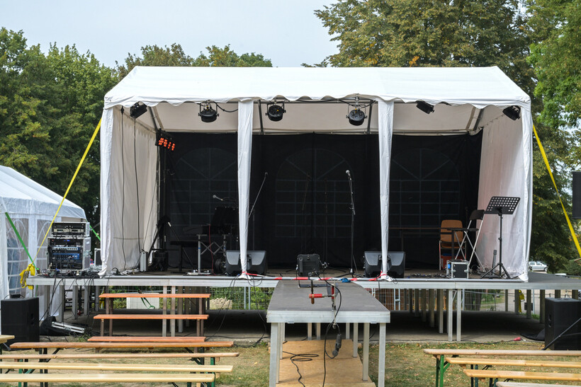 An outdoor music stage and bench seating under pack-down at an events venue. - event planning tasks
