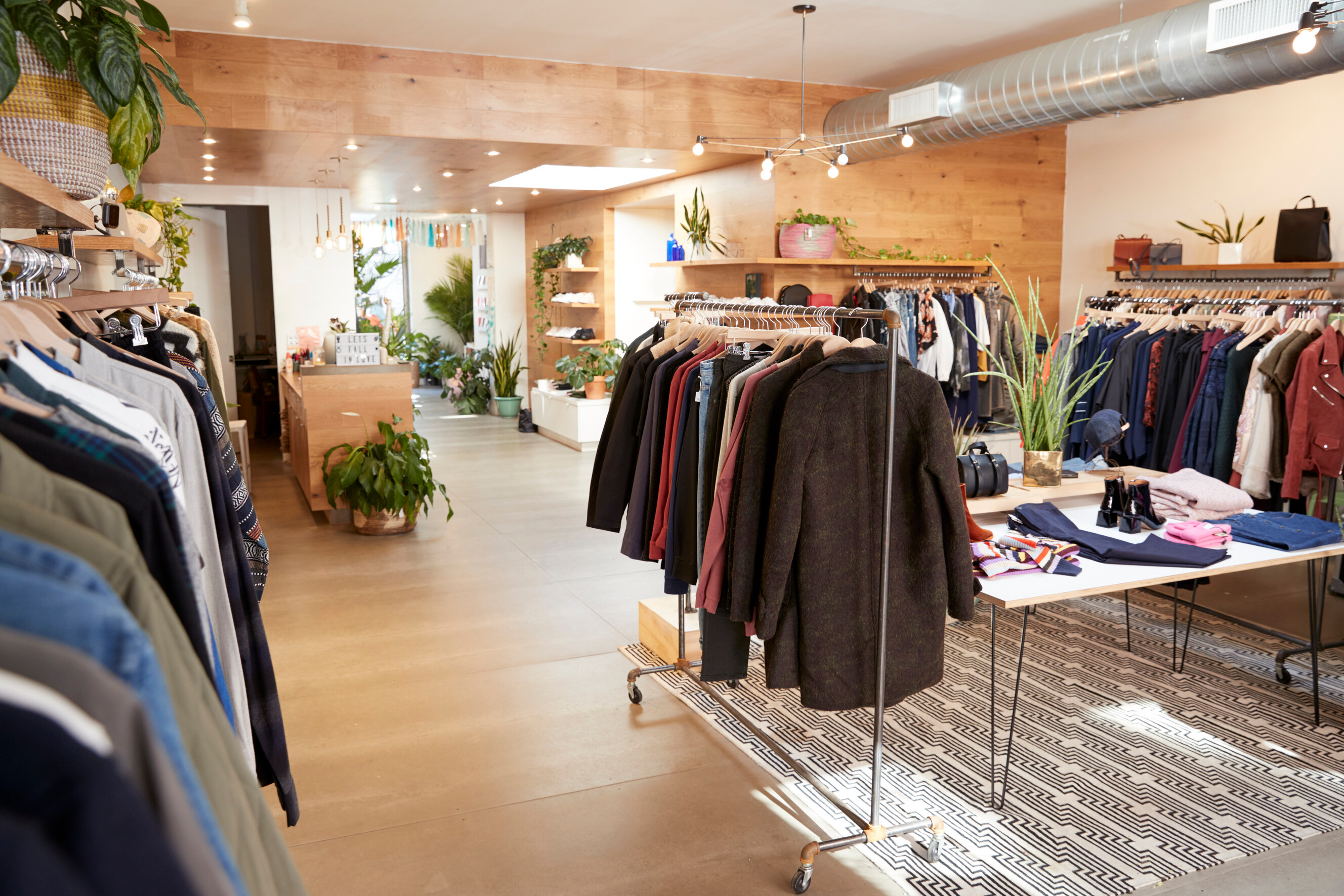 A bright boutique interior with neatly arranged clothing racks and shelving.