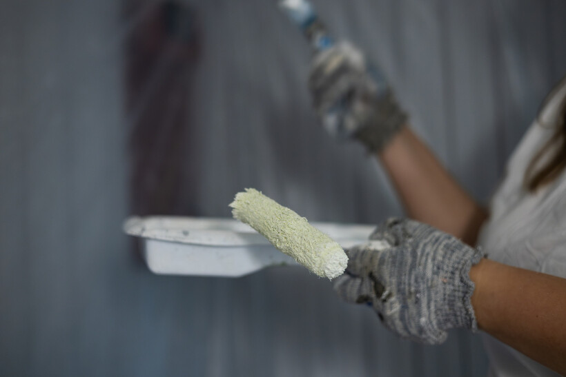 A painter holding a paint tray and roller for interior touch-ups. - retail tasks
