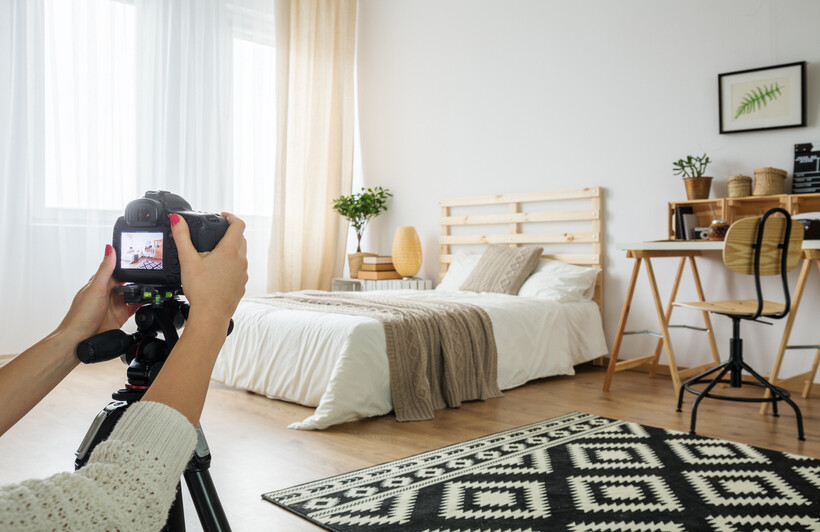 A person taking a photo of a styled bedroom with a camera. - property manager tasks