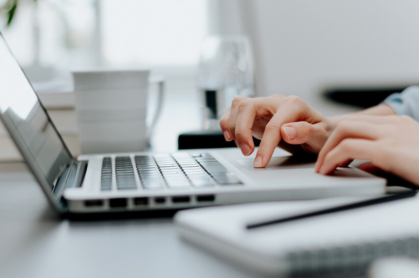 A close-up shot of hands working on a laptop during admin tasks. - property manager tasks