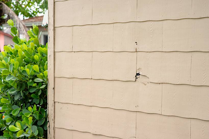 how to identify asbestos - Beige exterior cladding with a damaged section