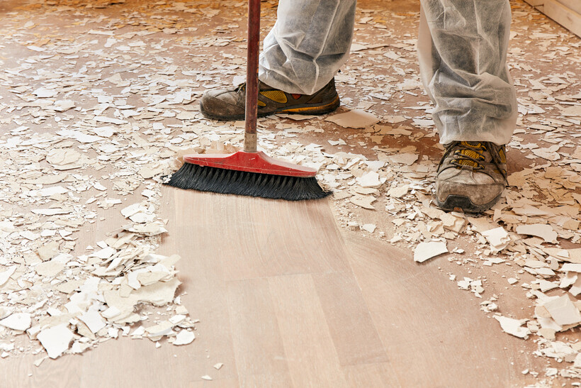 Tradie sweeping construction dust and debris off a freshly laid floor after a renovation. - after builders cleaning