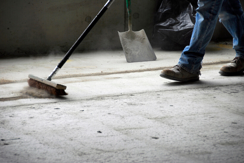 Construction site worker clearing away dust and rubble with a broom during cleanup. - after builders cleaning
