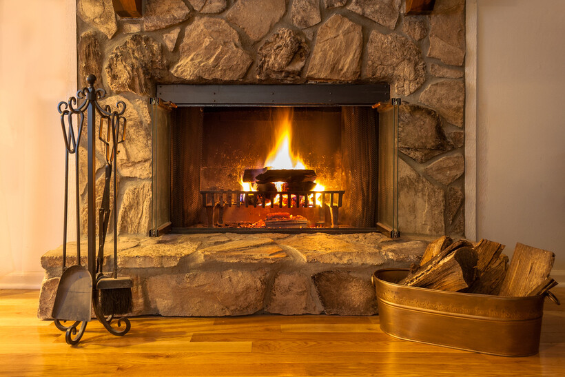A traditional wood fireplace set into a stone surround at home. - types of fireplaces in Australia