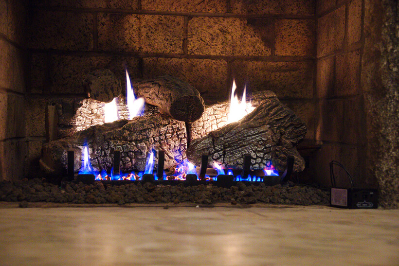 Stone-set gas fireplace with realistic flames warming a living space. - modern fireplaces